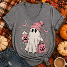 Load image into Gallery viewer, A heather gray V-neck t-shirt with a graphic of a cute cartoon ghost wearing a pink knit beanie and holding a jack-o'-lantern drink and shopping bag. The shirt is styled in a flat-lay arrangement with autumn props including pumpkins, fall leaves, pinecones, a plaid blanket, and a coffee cup.
