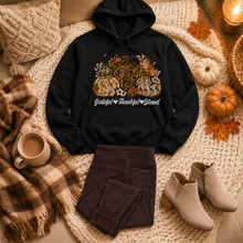Load image into Gallery viewer, Black Grateful Thankful Blessed pumpkin graphic hoodie styled with folded brown fleece-lined leggings and taupe ankle booties in a cozy fall home flat lay.