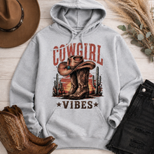 Load image into Gallery viewer, Cowgirl Vibes western graphic apparel featuring cowboy boots, cowgirl hat, cacti and desert sunset design
