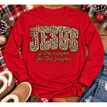 Load image into Gallery viewer, Jesus Is the Reason for the Season Christmas graphic shirt featuring bold leopard print JESUS lettering, decorative gold bows, and gold script. Faith-inspired holiday apparel available in red and black with four style options.
