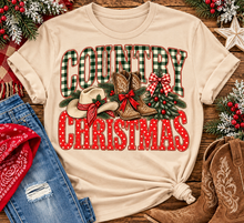 Load image into Gallery viewer, Country Christmas graphic tee with green plaid lettering, red polka dots, cowboy boots, western hat and festive Christmas bows.
