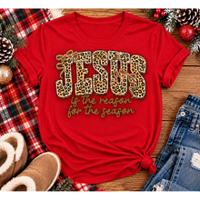Load image into Gallery viewer, Jesus Is the Reason for the Season Christmas graphic shirt featuring bold leopard print JESUS lettering, decorative gold bows, and gold script. Faith-inspired holiday apparel available in red and black with four style options.
