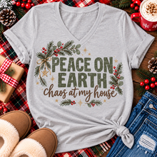 Load image into Gallery viewer, Peace on Earth Chaos at My House funny Christmas graphic apparel featuring distressed olive green lettering, rustic pine greenery, red berries and gold stars, available in sand and sport grey in short sleeve crewneck tees, V-neck tees, sweatshirts and hoodies.
