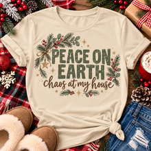 Load image into Gallery viewer, Peace on Earth Chaos at My House funny Christmas graphic apparel featuring distressed olive green lettering, rustic pine greenery, red berries and gold stars, available in sand and sport grey in short sleeve crewneck tees, V-neck tees, sweatshirts and hoodies.
