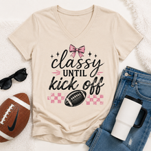 Load image into Gallery viewer, Cream V-neck Classy Until Kickoff football graphic tee featuring a pink bow, black football, pink checkerboard pattern and black and pink lettering.
